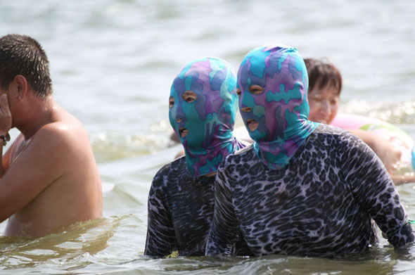 Women wear face masks and full body wetsuits for day at the beach, Qingdao, Shandong province, China - 16 Aug 2012