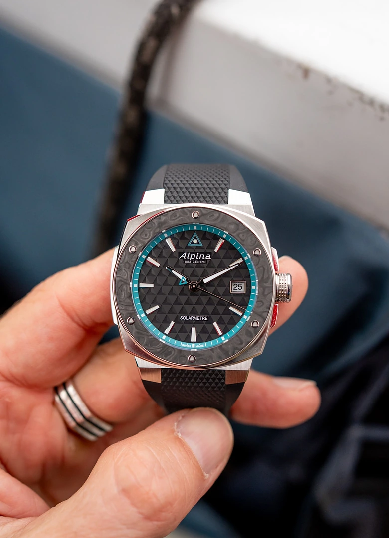 L'Alpina Alpiner Extreme Solarmetre Route du Rhum tenue en main, cadran noir à motif triangulaire et réhaut turquoise