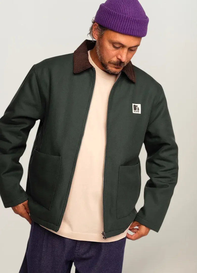 Blouson homme Olow Yarm vert mélèze en canvas à col en velours marron, porté avec un bonnet violet