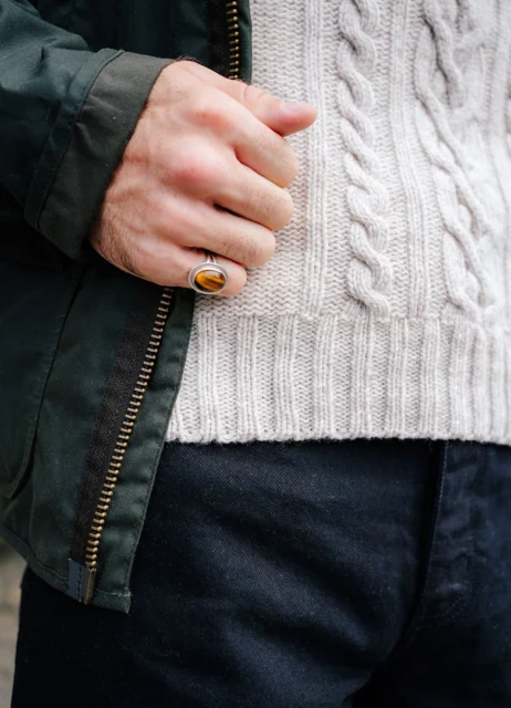 Contraste de matières en automne : maille torsadée en laine, veste en toile cirée et denim brut