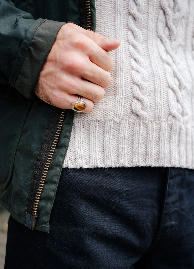 Contraste de matières en automne : maille torsadée en laine, veste en toile cirée et denim brut