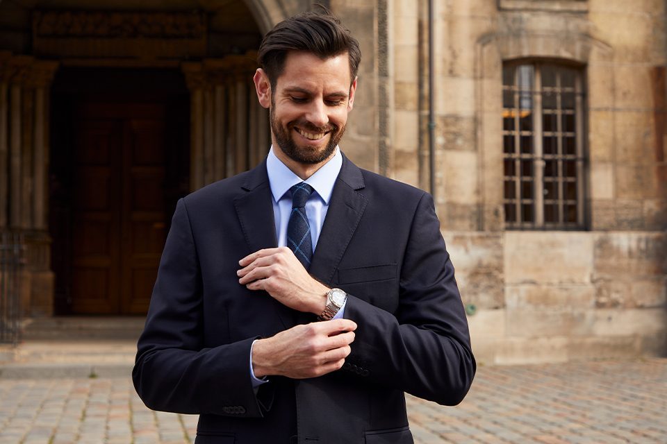 homme en costume devant une église montre