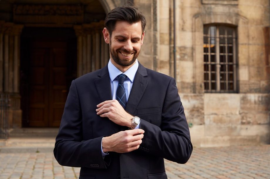 homme en costume devant une église montre