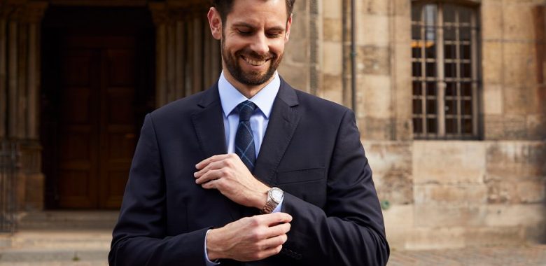 homme en costume devant une église montre